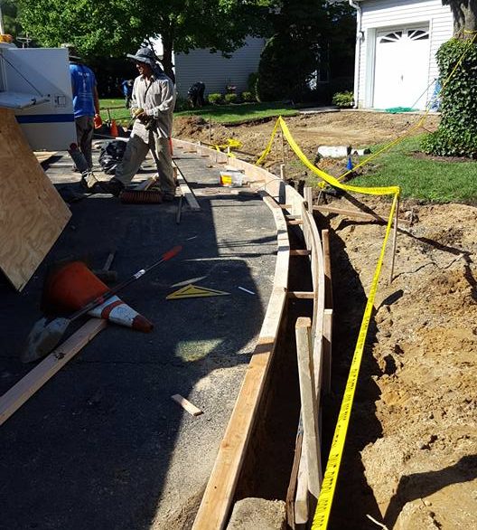 Trench and forms set for drainage work beside a driveway