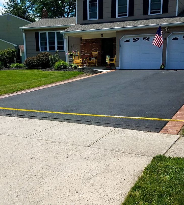 Finished asphalt driveway with a Pave Patrol yard sign