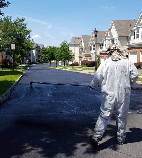 Technician spraying sealcoat on a residential street in New Jersey