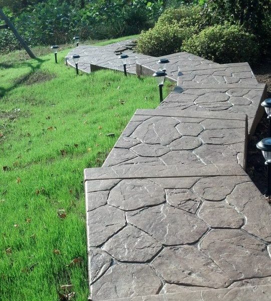 Curved stamped concrete retaining wall along a lawn